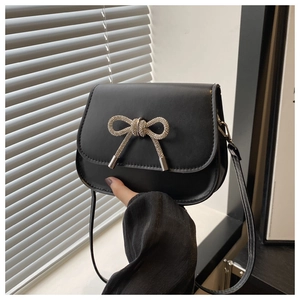 Detail of a vintage black PU leather crossbody bag featuring a rhinestone butterfly buckle