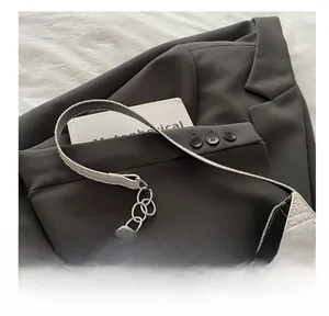 Close-up of the elegant crocodile texture and metal chain strap on a white underarm bag