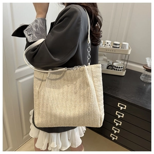 Detail view of cream woven straw tote bag with herringbone pattern and chain strap