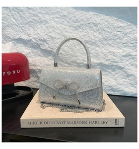 Close-up of sparkling silver sequin handbag with rhinestone bow detail and metal handle