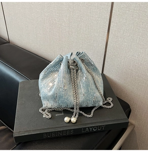 Detail of light blue sequined bucket bag with silver chain and white pearl drawstring