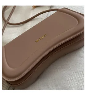 Detailed close-up of textured tan leather bag with fine stitching and golden brand logo