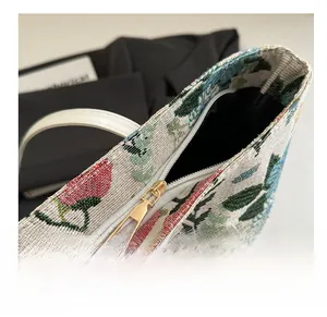 Detailed close-up of smooth gold-tone zipper on floral jacquard shoulder bag