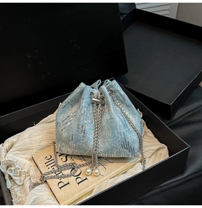 Detail of light blue sequin bucket bag with pearl drawstring and silver chain in gift box