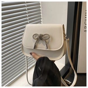 Detail of white PU crossbody bag featuring a silver rhinestone butterfly clasp and flap
