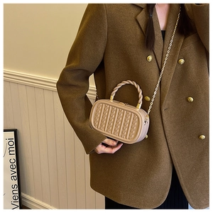 Detail of beige chain bag with cable knit texture and gold twisted metal handle