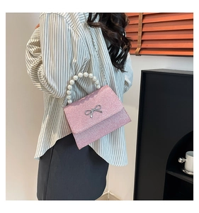 Pink sequin handbag with silver metal bow and large faux pearl top handle close-up