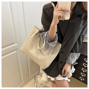 Detailed close-up of a woven straw tote bag featuring fine V-pattern beige texture