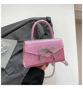Detail shot of a pink sequin evening bag featuring a crystal bow and silver metal chain