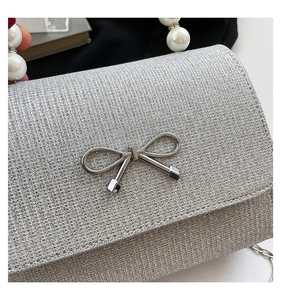Macro detail of silver sequin evening bag with metal bow and pearl top handle