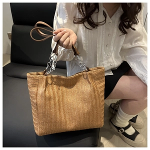 Close-up of large straw tote bag featuring refined V-shaped weave and chain strap