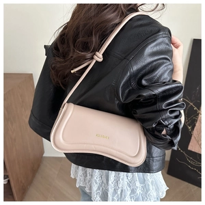 Detail of beige shoulder bag featuring a golden logo and stylish knotted strap detail