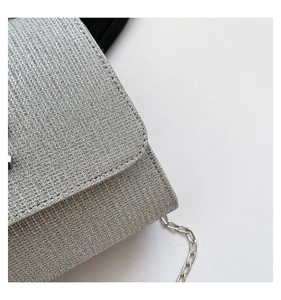 Close-up of the silver glitter woven texture and metal chain strap on this elegant handbag