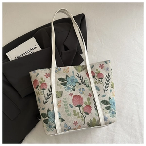 Detail of floral jacquard tote bag with white faux leather straps and vintage patterns