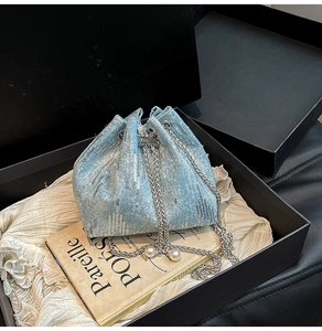 Detail of light blue sequined bucket bag with silver chain strap and pearl drawstring accents