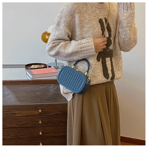 Macro detail of dark blue crossbody box bag with cable knit texture and gold chain