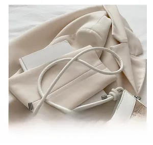 Détail de la bandoulière fine en cuir blanc et texture tissée du sac seau