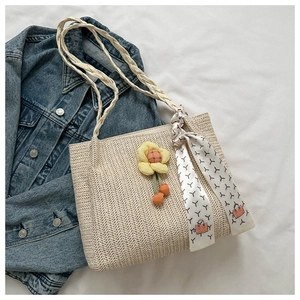 Detail of woven straw tote bag texture with floral charm and printed scarf handle