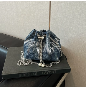 Detail of denim bucket bag with silver sequin wing pattern and pearl drawstring chain