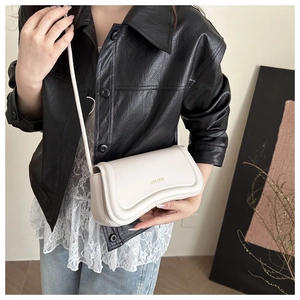 Detail shot of a white wave-shaped leather shoulder bag featuring a gold brand logo