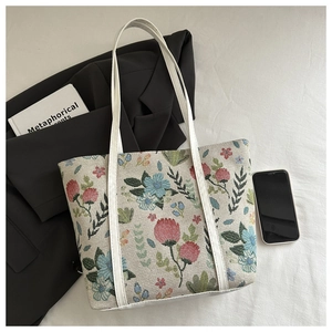 Detailed view of floral jacquard tote bag with white leather straps and vintage patterns