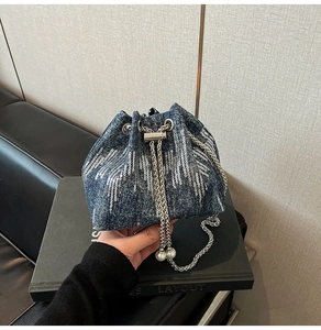 Close-up of denim bucket bag with silver sequins, chain drawstring, and pearl details