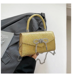 Detail of sparkling gold sequin evening bag featuring a crystal bow and silver chain