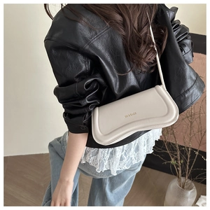 Detailed back view of a minimalist cream shoulder bag worn with a black leather jacket
