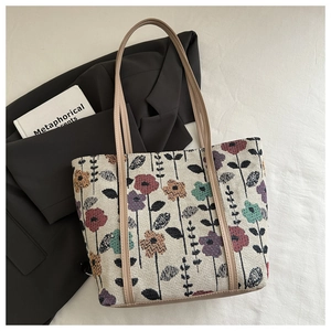 Detail of floral embroidery on a woven tote bag with leather straps and professional styling