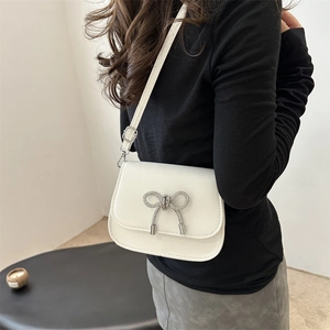 Fashionable white crossbody bag with rhinestone butterfly detail shown on shoulder