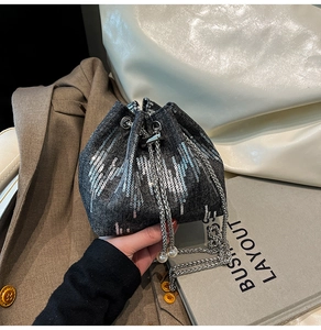 Detail of dark grey denim bucket bag featuring silver sequins and pearl chain strap