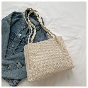 Detail of hand-woven beige straw tote bag with braided handles and summer style textures