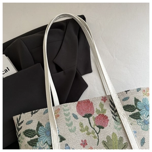 Detail of floral tapestry shoulder bag with woven fabric texture and slim leather straps