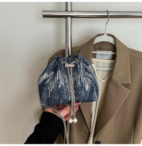 Detail of denim bucket bag with silver sequin patterns and elegant pearl drawstring