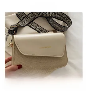 Detail of woven texture handbag with wide patterned strap and golden metal buckle