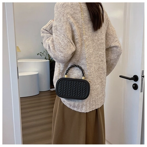 Fashionable black textured crossbody bag with gold chain strap shown on model in studio