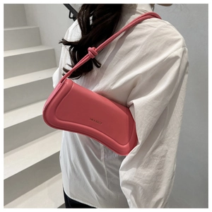 Shoulder view of a pink leather hobo bag with a knotted strap and XM & BAGS branding
