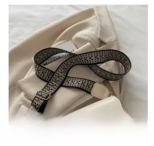 Detail of wide woven jacquard shoulder strap with geometric patterns and golden metal buckle