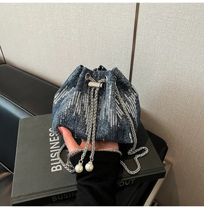 Close-up of blue denim bucket bag with silver sequins and pearl drawstring detail