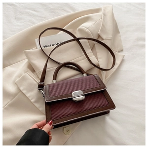 Détail d'un sac à main tissé contrasté avec fermoir métallique argenté sur blazer beige