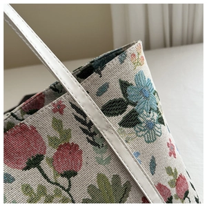 Macro detail of floral jacquard fabric and white leather strap with stitching