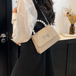 Elegant champagne glitter handbag with pearl handle and silver bow detail for party wear