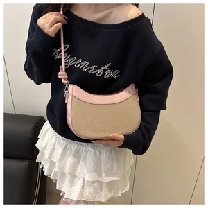 Détail du sac à main en toile et cuir rose porté à l'épaule dans une tenue élégante