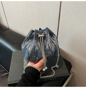 Detail of denim bucket bag with silver sequin tassels and elegant pearl drawstring