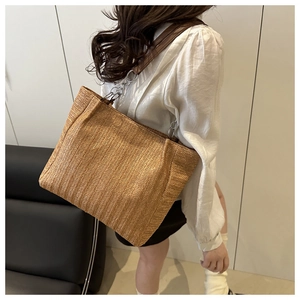 Detail of woven straw tote bag with brown leather straps and silver chain link accents