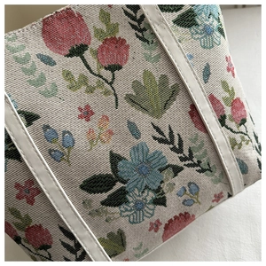 Close-up of vintage floral tapestry fabric and white leather trim on a shoulder bag