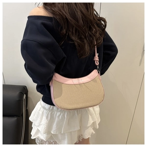 Détail de la bordure en cuir rose avec texte et tissu beige tissé sur le sac hobo