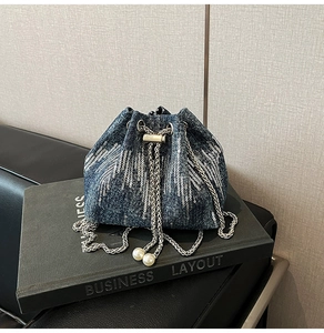 Close-up of denim bucket bag featuring silver sequins and pearl chain drawstring