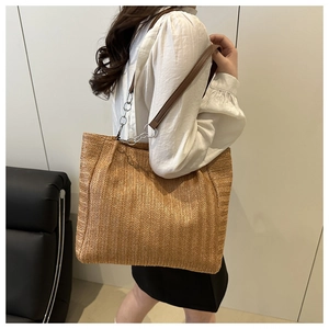 Detail of hand-woven straw tote bag with silver chain and brown leather strap