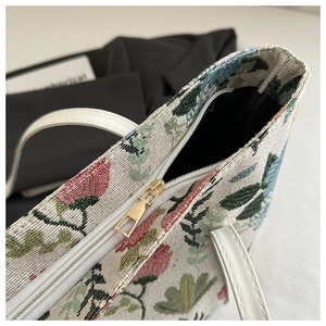 Detailed macro of golden zipper and floral jacquard texture on stylish shoulder bag